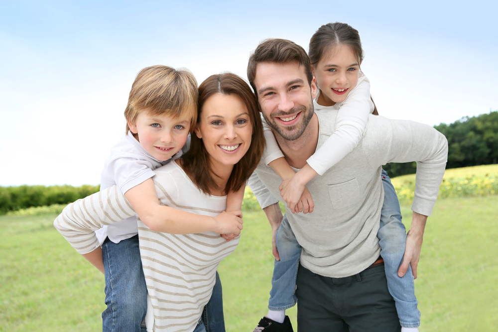 Young parents giving piggyback ride to kids